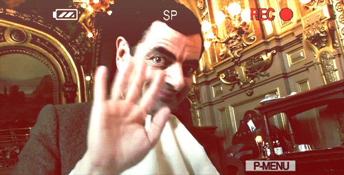 GIF of the character Mr. Bean waving awkwardly at the viewer